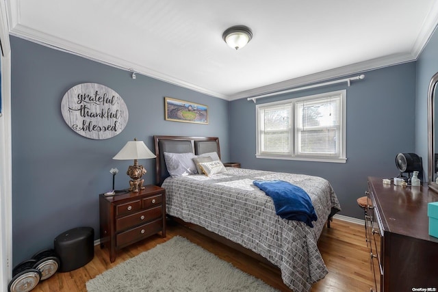 bedroom featuring crown molding, wood finished floors, and baseboards