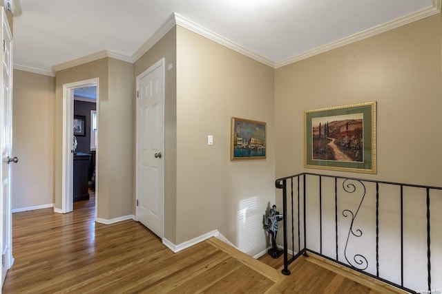 hallway with ornamental molding, baseboards, and wood finished floors