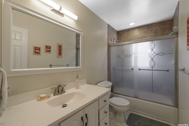 full bath with vanity, toilet, and combined bath / shower with glass door