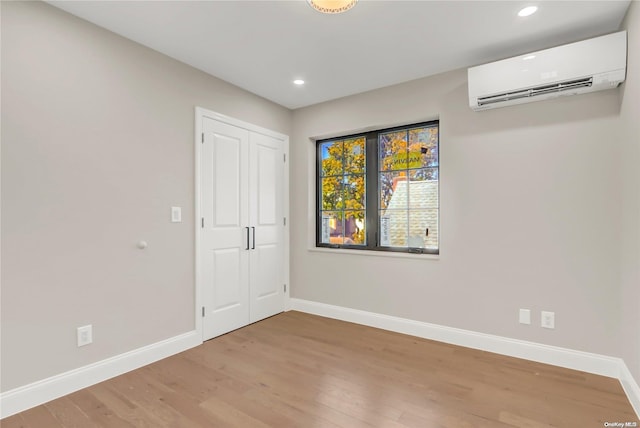 unfurnished room featuring a wall mounted AC and wood-type flooring