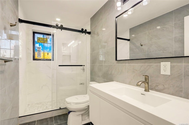 bathroom with walk in shower, tile patterned floors, toilet, vanity, and tile walls