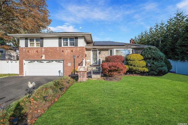 split level home with solar panels, a front lawn, and a garage