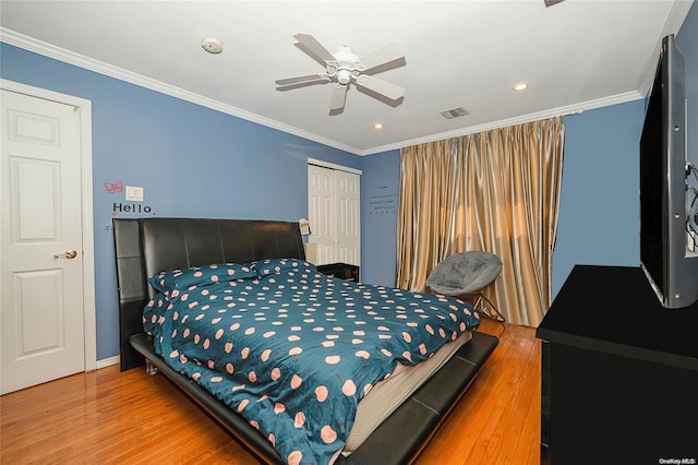 bedroom with a closet, ceiling fan, hardwood / wood-style floors, and crown molding