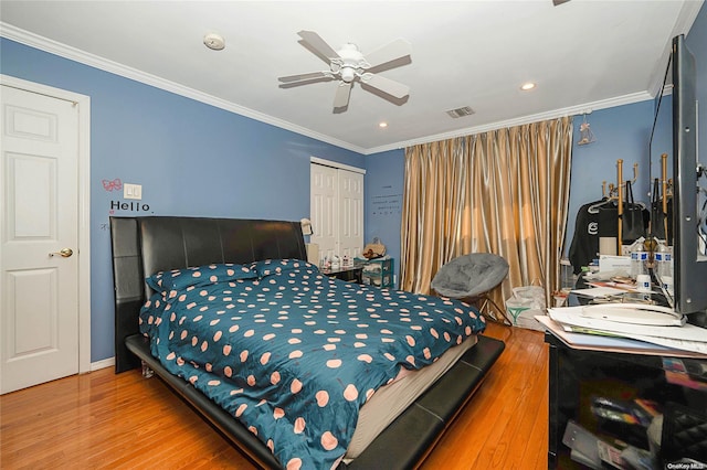 bedroom featuring a closet, hardwood / wood-style flooring, ceiling fan, and crown molding