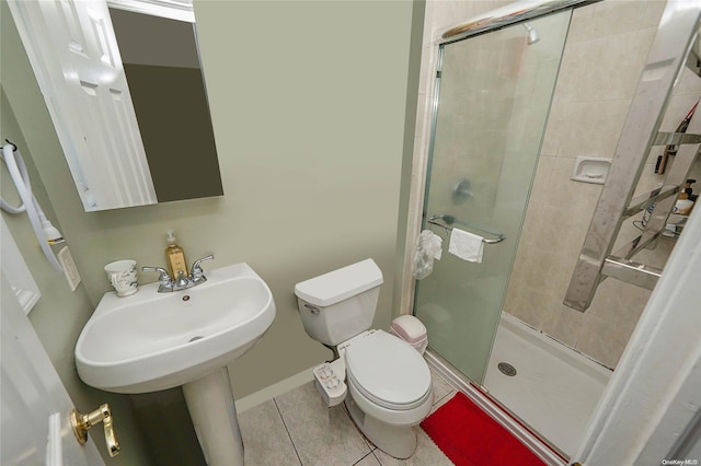 bathroom featuring toilet, tile patterned floors, a shower with door, and sink