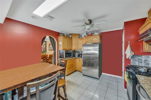 kitchen with appliances with stainless steel finishes, light stone counters, ornamental molding, ceiling fan, and light tile patterned floors