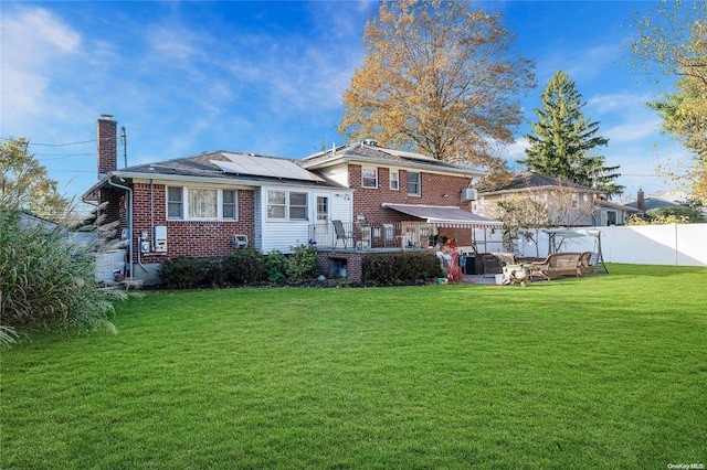 rear view of property featuring solar panels and a lawn