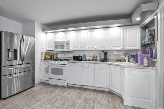 kitchen featuring decorative backsplash, white cabinetry, and white appliances