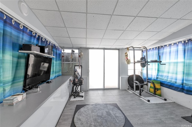 exercise room featuring a paneled ceiling and a wall of windows