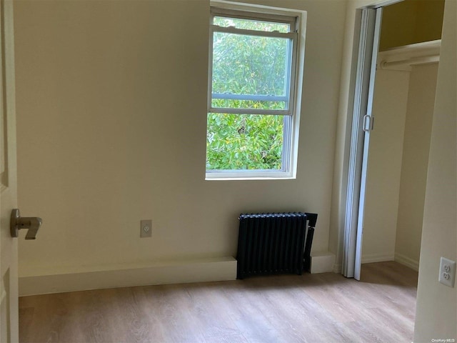 unfurnished room featuring radiator heating unit and light hardwood / wood-style floors