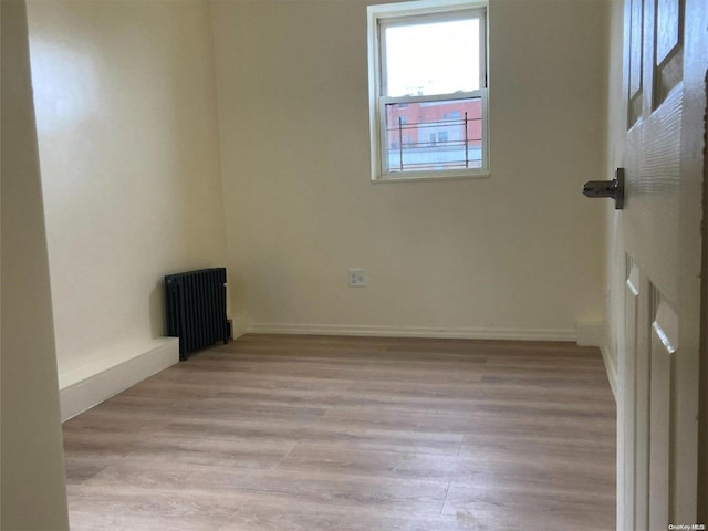 empty room with light hardwood / wood-style floors and radiator