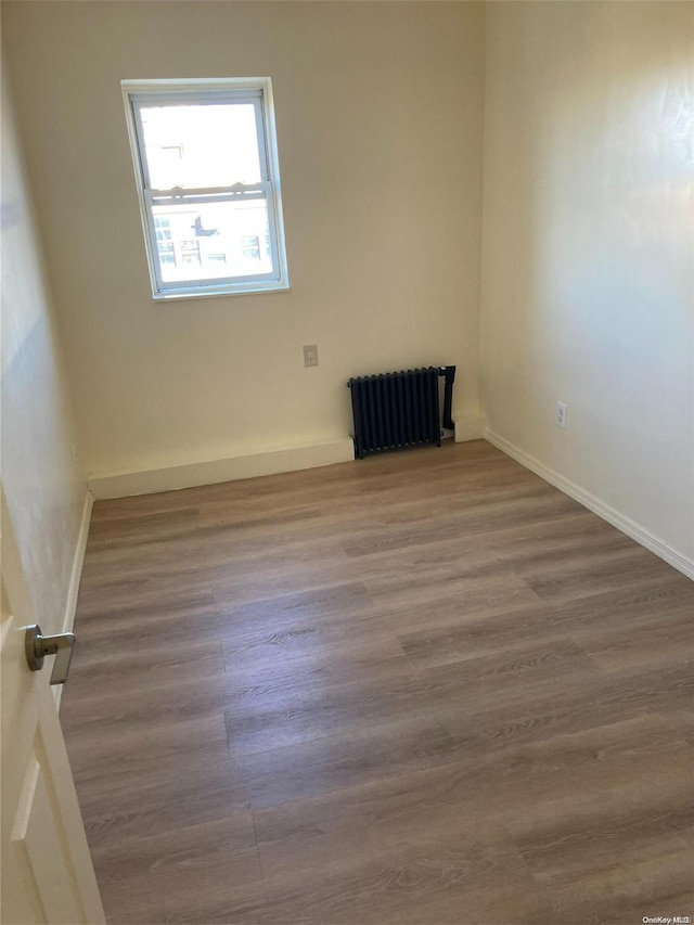 spare room with radiator heating unit and hardwood / wood-style floors