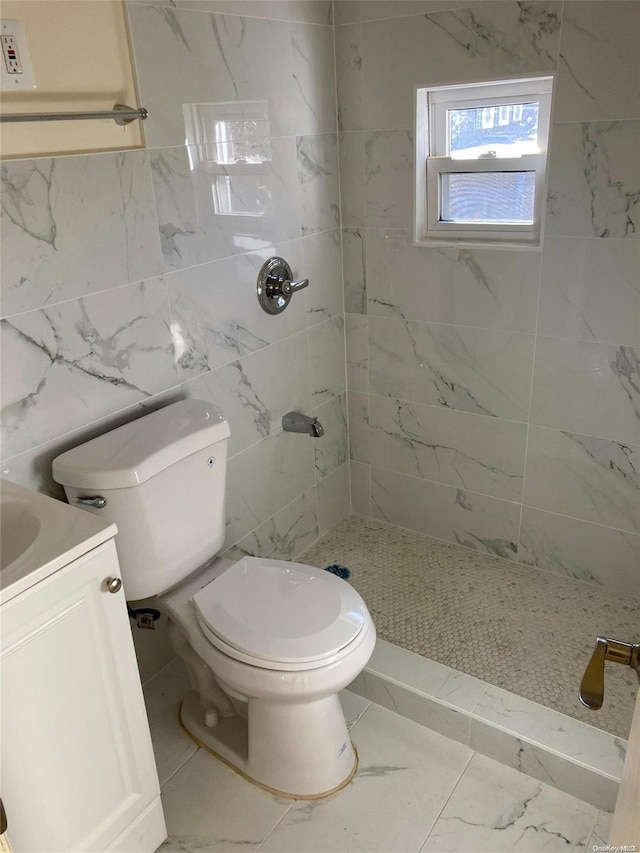 bathroom featuring a tile shower, vanity, tile walls, and toilet