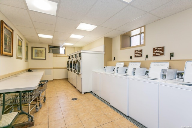 clothes washing area with washer and dryer, light tile patterned floors, and a wall unit AC