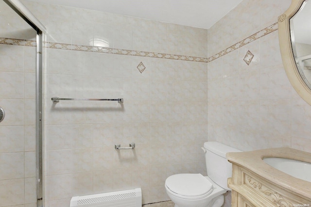 bathroom with radiator, vanity, tile walls, and toilet