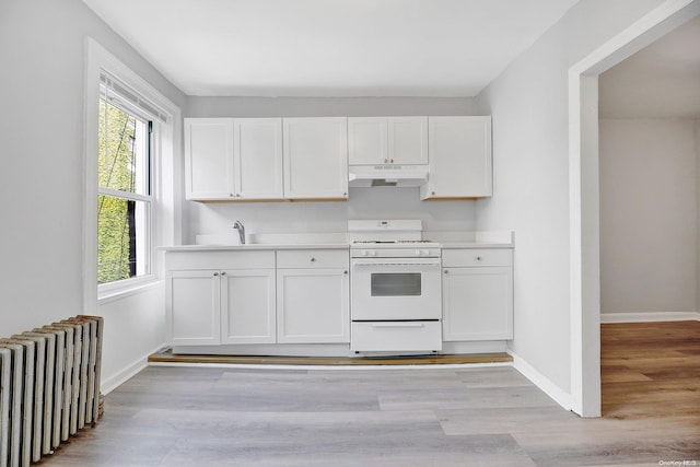 kitchen with white cabinets, white stove, light hardwood / wood-style floors, and radiator