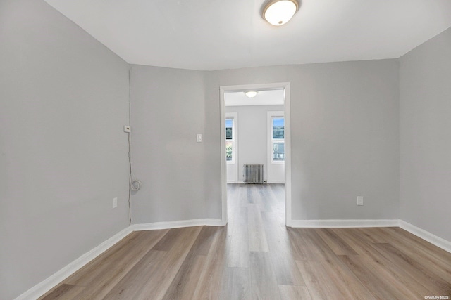 unfurnished room featuring radiator heating unit and light hardwood / wood-style flooring