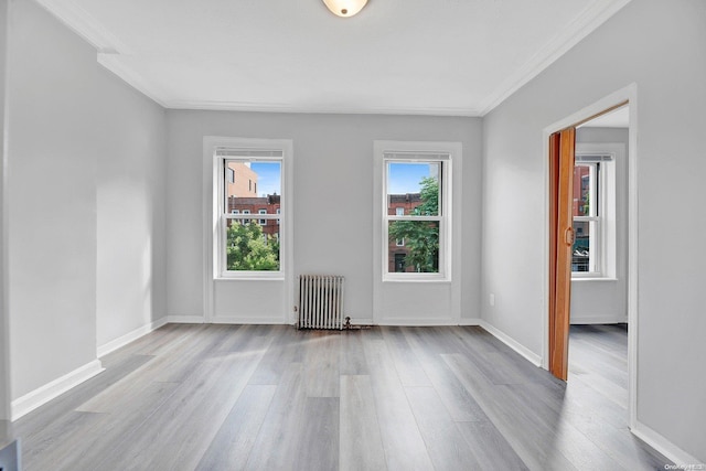 unfurnished room with crown molding, radiator heating unit, and light hardwood / wood-style floors