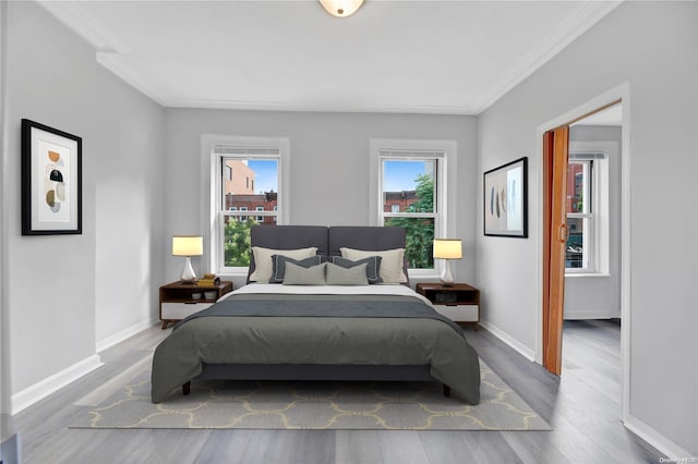 bedroom featuring multiple windows, crown molding, and hardwood / wood-style flooring