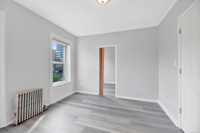 unfurnished room featuring light hardwood / wood-style floors, radiator heating unit, and crown molding