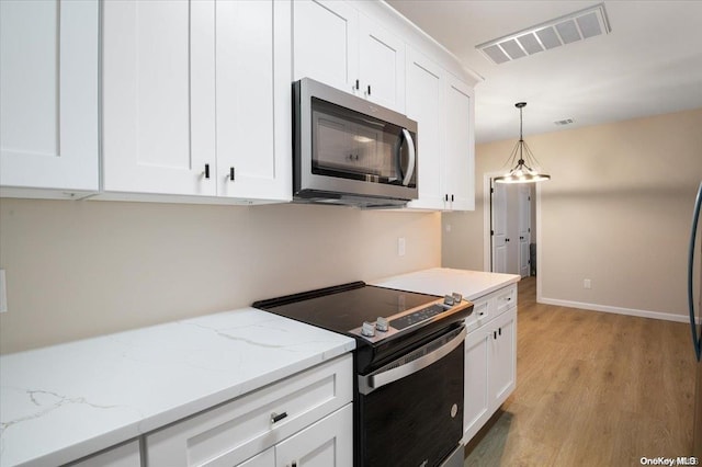 kitchen featuring appliances with stainless steel finishes, light wood-type flooring, decorative light fixtures, and white cabinetry