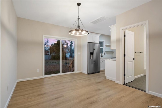 unfurnished dining area featuring a notable chandelier, light hardwood / wood-style floors, and sink