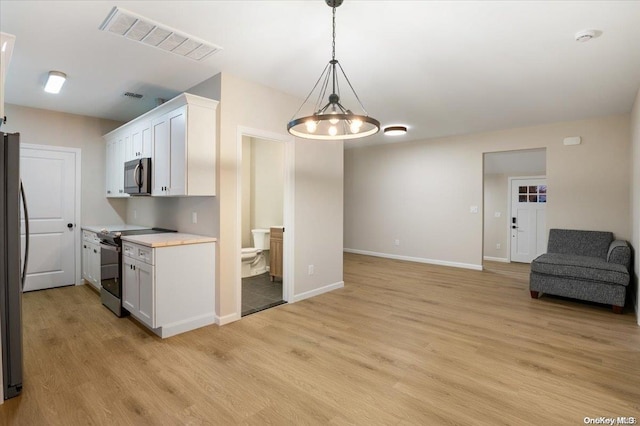 kitchen featuring appliances with stainless steel finishes, pendant lighting, an inviting chandelier, light hardwood / wood-style flooring, and white cabinets