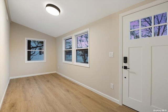 foyer entrance with vaulted ceiling and light hardwood / wood-style flooring