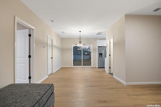 unfurnished dining area featuring light hardwood / wood-style floors and an inviting chandelier