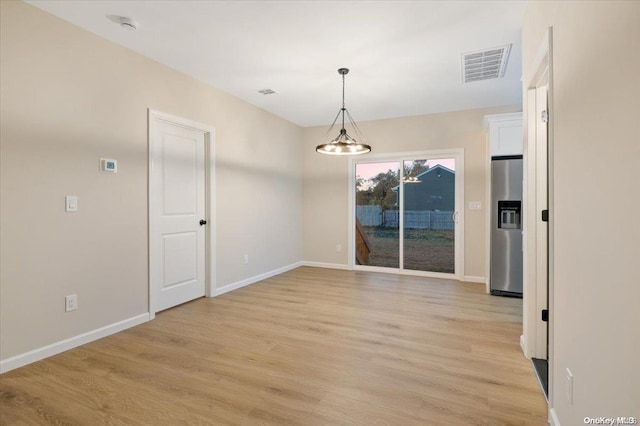 unfurnished dining area featuring light hardwood / wood-style flooring and a notable chandelier