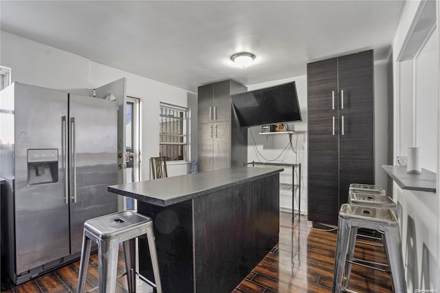 kitchen with a kitchen breakfast bar, stainless steel fridge, and dark hardwood / wood-style flooring