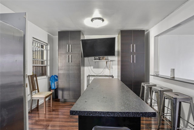 kitchen with dark hardwood / wood-style flooring, dark brown cabinetry, and a breakfast bar