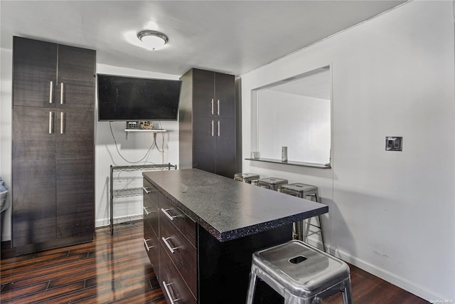 kitchen featuring dark hardwood / wood-style floors, a center island, dark brown cabinetry, and a breakfast bar area