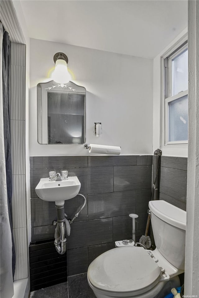 bathroom featuring sink, tile walls, and toilet