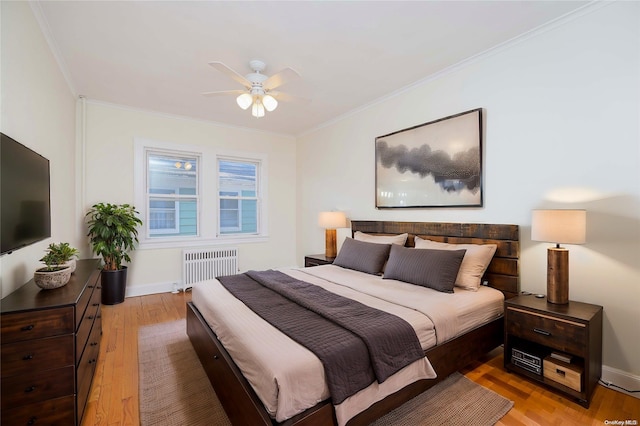 bedroom with crown molding, radiator heating unit, ceiling fan, and light hardwood / wood-style floors