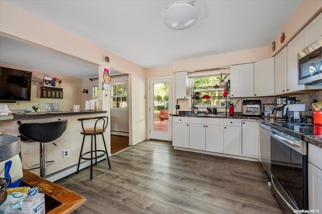 kitchen featuring dark wood-type flooring, white cabinetry, plenty of natural light, and stainless steel appliances