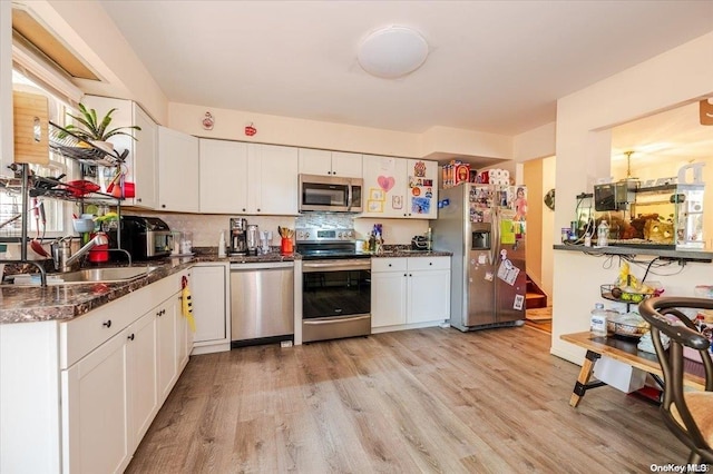 kitchen featuring white cabinetry, sink, tasteful backsplash, light hardwood / wood-style flooring, and appliances with stainless steel finishes