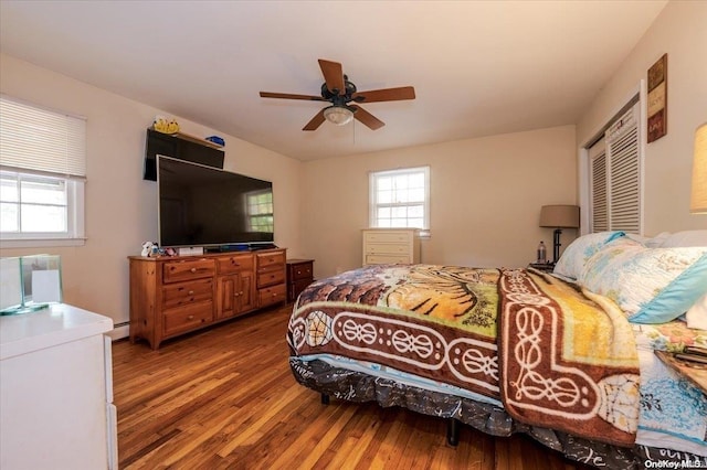 bedroom featuring wood-type flooring, a closet, ceiling fan, and a baseboard heating unit