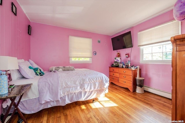 bedroom with light hardwood / wood-style floors and a baseboard radiator