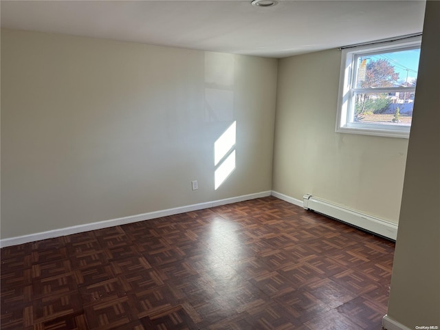 unfurnished room with dark parquet floors and a baseboard heating unit