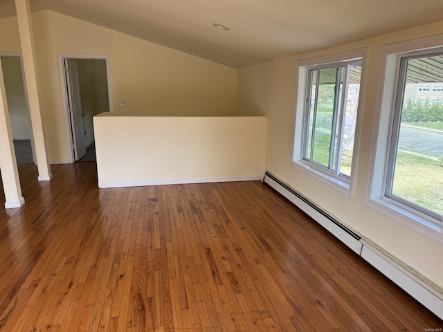 additional living space featuring a baseboard heating unit, hardwood / wood-style flooring, and lofted ceiling