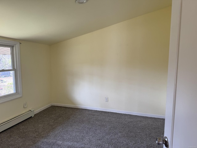 empty room featuring a baseboard heating unit, baseboards, and dark carpet