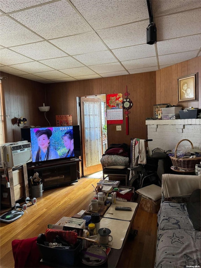 living room with a paneled ceiling, light hardwood / wood-style floors, and wooden walls