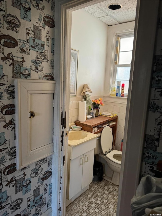 bathroom with vanity, tile walls, and toilet