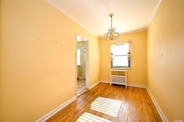 empty room featuring a chandelier, hardwood / wood-style flooring, and crown molding