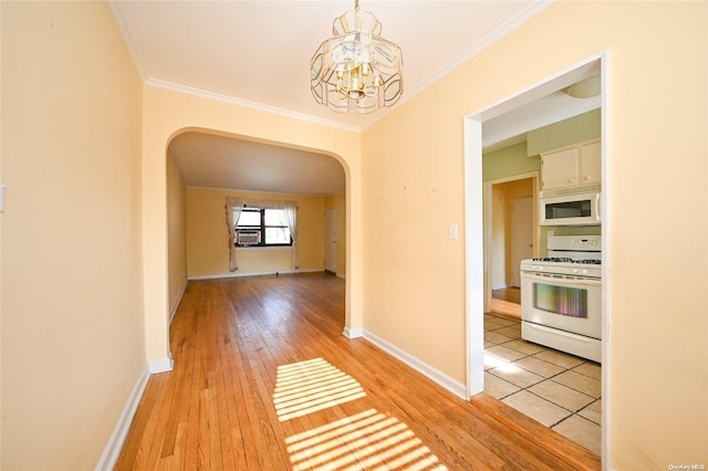 hallway with crown molding, light hardwood / wood-style floors, and an inviting chandelier