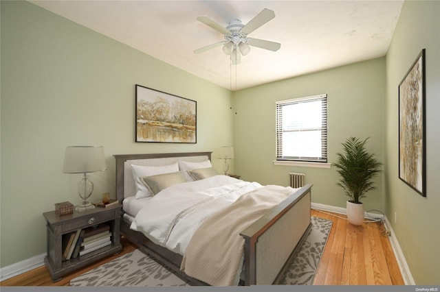 bedroom featuring ceiling fan, radiator heating unit, and light hardwood / wood-style flooring