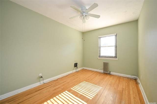 spare room with radiator heating unit, ceiling fan, and wood-type flooring