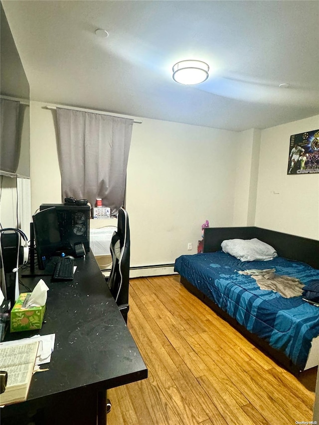 bedroom featuring hardwood / wood-style flooring and baseboard heating