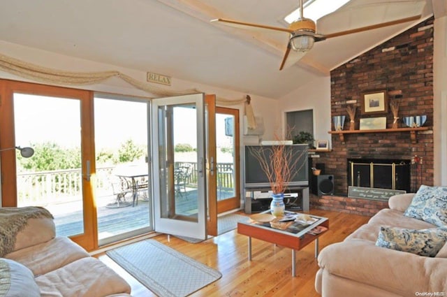 living room with ceiling fan, french doors, a brick fireplace, vaulted ceiling, and light wood-type flooring